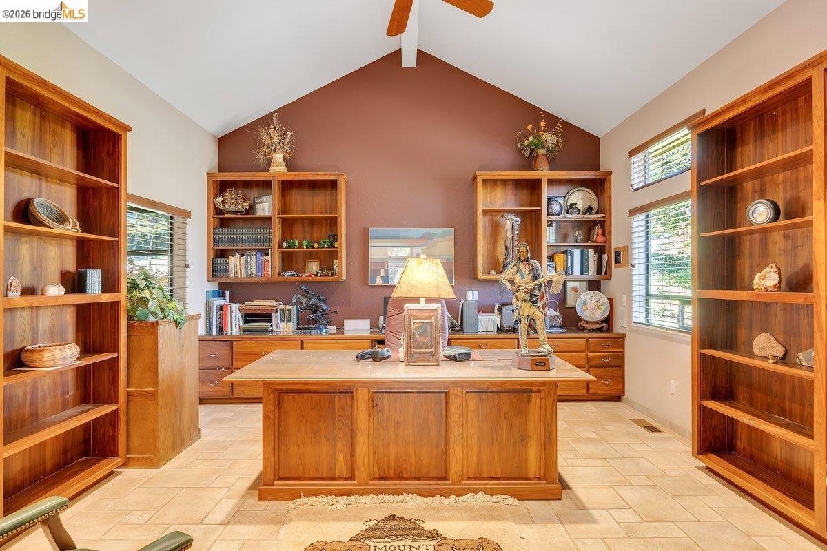 13700 Clements Road Groveland, CA 95321 - Photo 22 of 93 Office space featuring vaulted ceilings, built-in wooden shelving, a wood-finish desk, ceramic tile flooring, and multiple windows