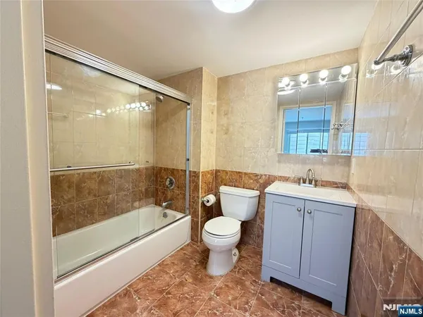 a bathroom with a bathtub shower sink mirror and toilet