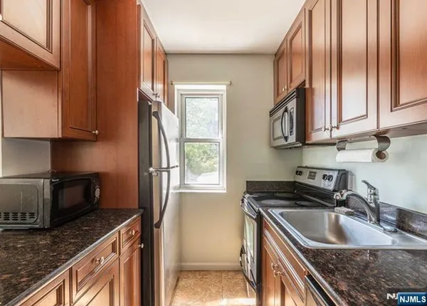 a kitchen with granite countertop stainless steel appliances a sink a stove and a refrigerator