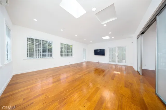 a view of empty room with wooden floor and windows