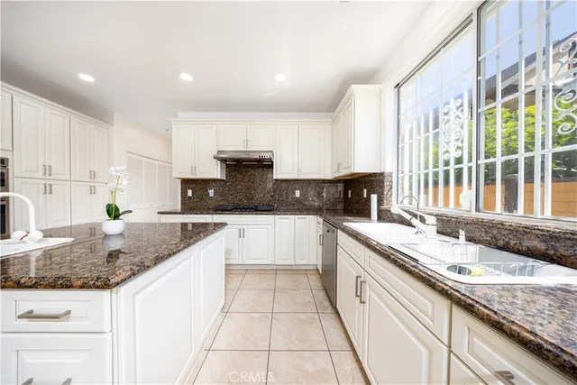 a large kitchen with granite countertop a sink a counter top space appliances and cabinets