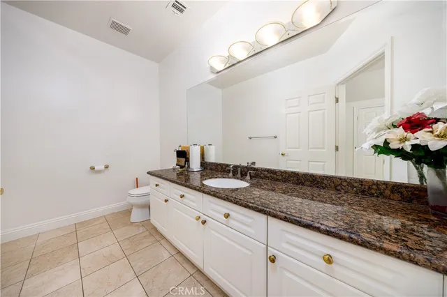 a spacious bathroom with a granite countertop sink and a white cabinets