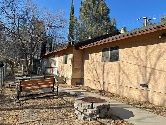 a backyard of a house with wooden fence and large trees