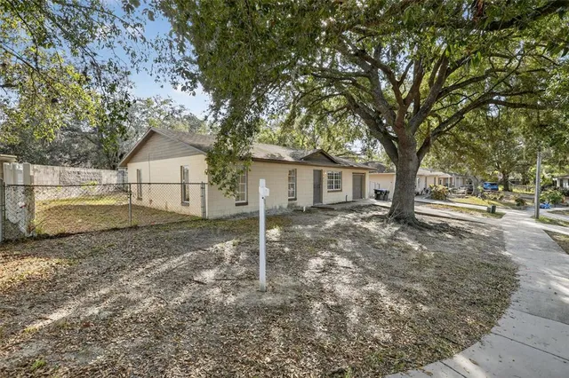 a view of a house with a yard and large tree