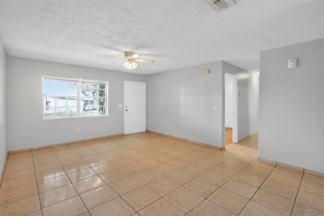 an empty room with windows and fan