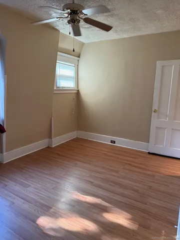 an empty room with wooden floor fan and windows