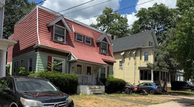 a front view of a house with garden and trees