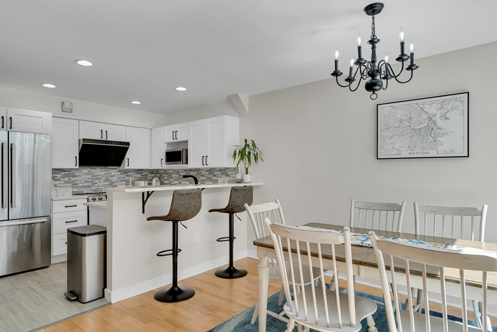 a kitchen with stainless steel appliances kitchen island granite countertop a dining table chairs sink and cabinets