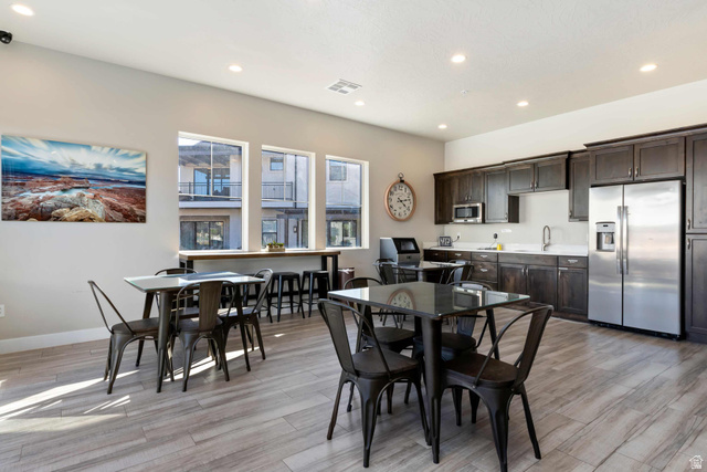2600 Ocotillo Way, Unit 31 Santa Clara, UT 84765 - Photo 58 of 73 Open-concept gathering space featuring wood-finish flooring, a full kitchen with dark cabinetry and stainless steel appliances, and a wall of three large windows