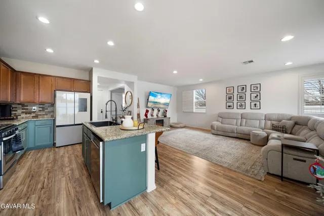 a large living room with stainless steel appliances granite countertop furniture and a wooden floors