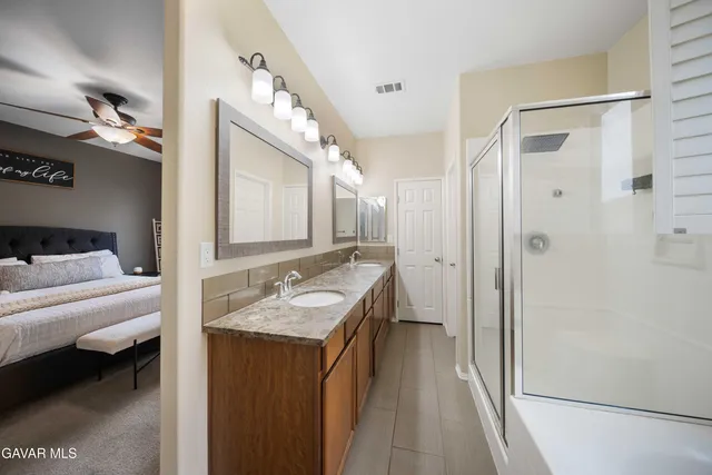 a en suite bathroom with a double vanity sink a mirror and shower
