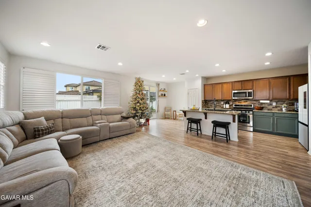 a living room with furniture wooden floor and kitchen view