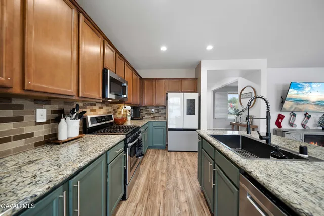 a kitchen with granite countertop stainless steel appliances sink stove microwave and cabinets