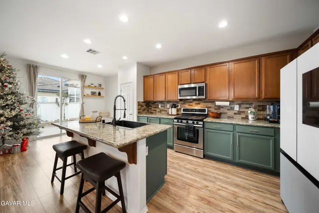 a kitchen with stainless steel appliances granite countertop a stove top oven a sink dishwasher a dining table and chairs with wooden floor