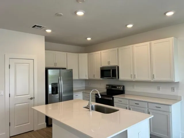 a kitchen with a refrigerator a microwave a sink and cabinets