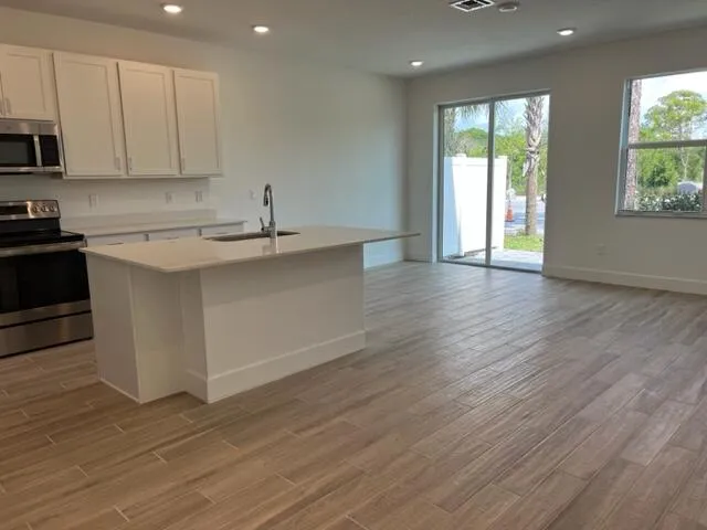 a kitchen with stainless steel appliances granite countertop a sink a stove and a wooden floors