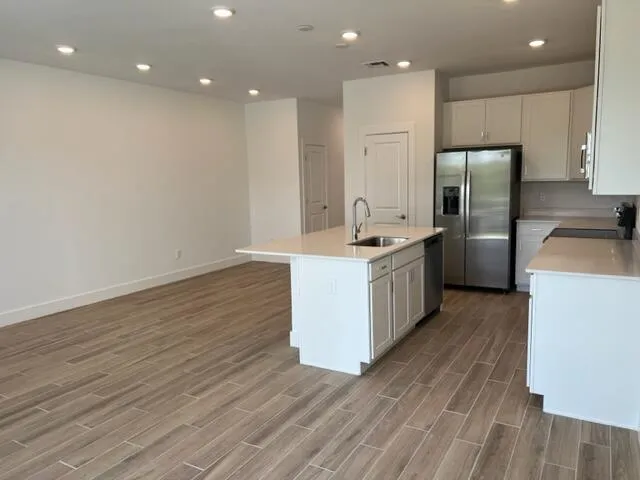 a kitchen with a sink stainless steel appliances wooden floor and cabinets