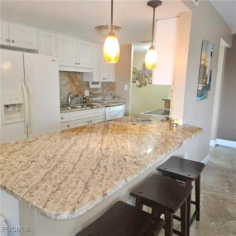 a view of kitchen island with granite countertop sink refrigerator dining table and chairs