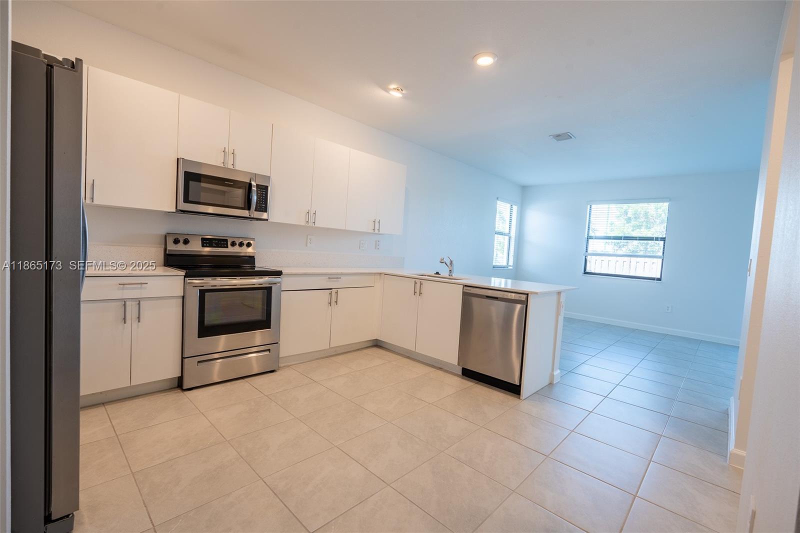 24720 Southwest 119th Place, Unit 24720 Homestead, FL 33032 - Photo 10 of 30 a kitchen with kitchen island granite countertop a stove top oven and sink
