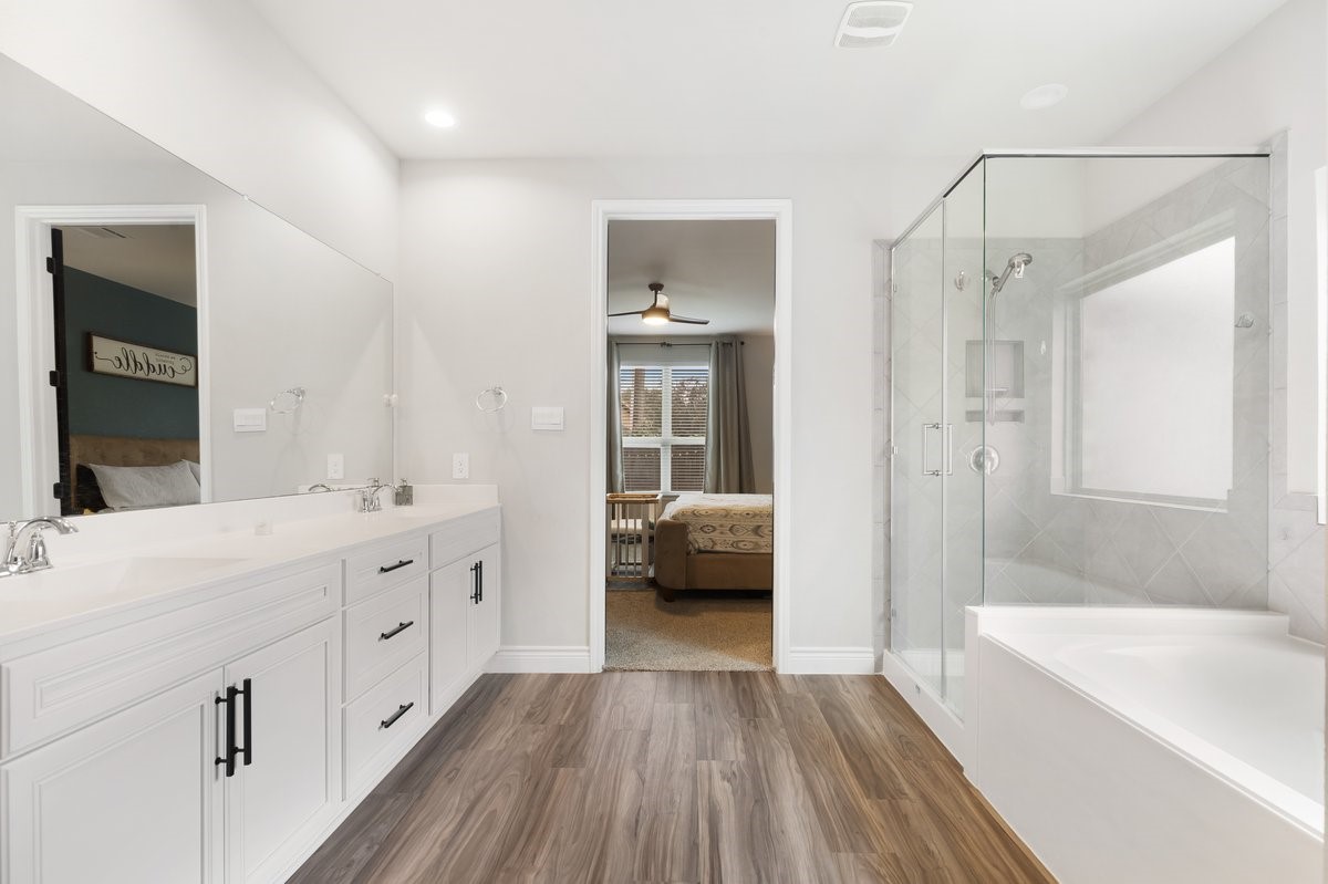 15815 Gibson Grass Court Spring, TX 77379 - Photo 14 of 26 The primary bathroom is filled with natural light, featuring a freestanding shower and a luxurious soaking tub.