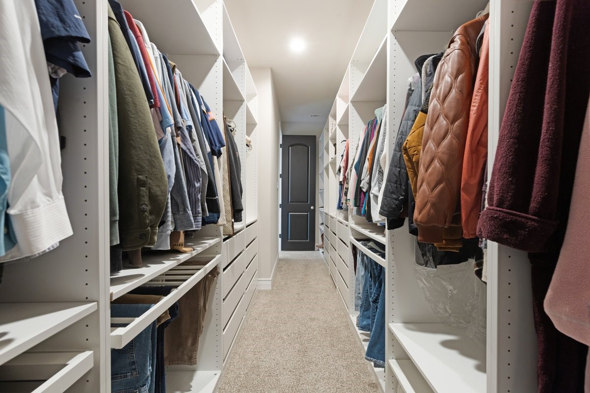 15815 Gibson Grass Court Spring, TX 77379 - Photo 15 of 26 Long primary closet with thoughtfully designed custom shelving and drawers, including glass-front displays and designated areas for clothing, shoes pursed, belts and more!
