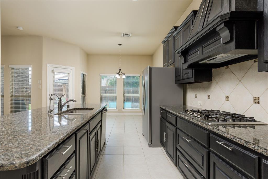 404 Tanner Square McKinney, TX 75072 - Photo 12 of 34 Kitchen with appliances with stainless steel finishes, a sink, backsplash, dark stone countertops, and hanging light fixtures