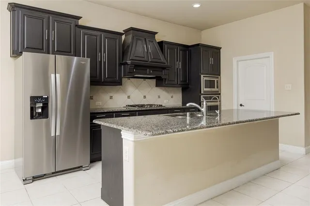 a kitchen with stainless steel appliances granite countertop a refrigerator and a sink