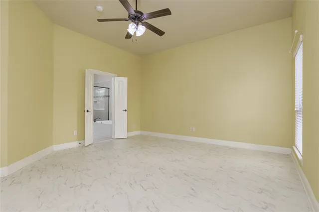 a view of an empty room and chandelier fan