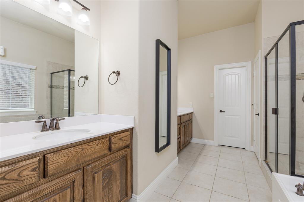 404 Tanner Square McKinney, TX 75072 - Photo 17 of 34 Bathroom featuring a shower stall, two vanities, and tile patterned flooring