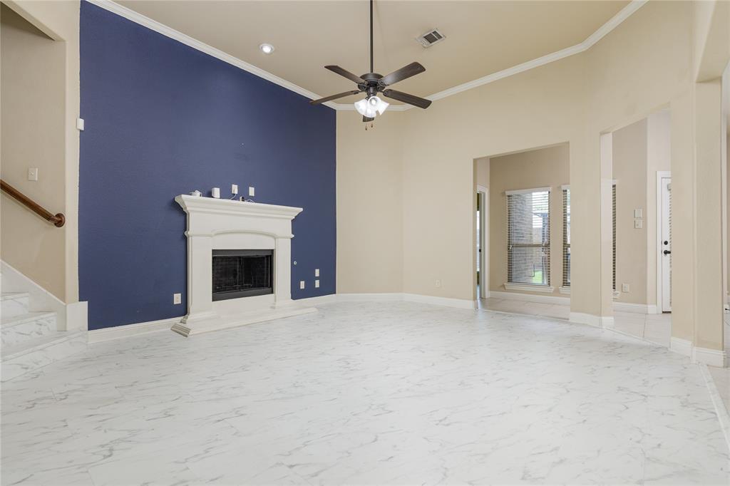 404 Tanner Square McKinney, TX 75072 - Photo 7 of 34 Unfurnished living room featuring marble finish flooring, ornamental molding, ceiling fan, a fireplace with raised hearth, and stairs