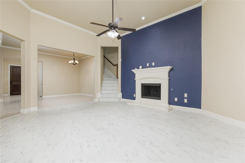 404 Tanner Square McKinney, TX 75072 - Photo 8 of 34 Unfurnished living room with ornamental molding, a chandelier, stairs, a fireplace with raised hearth, and ceiling fan