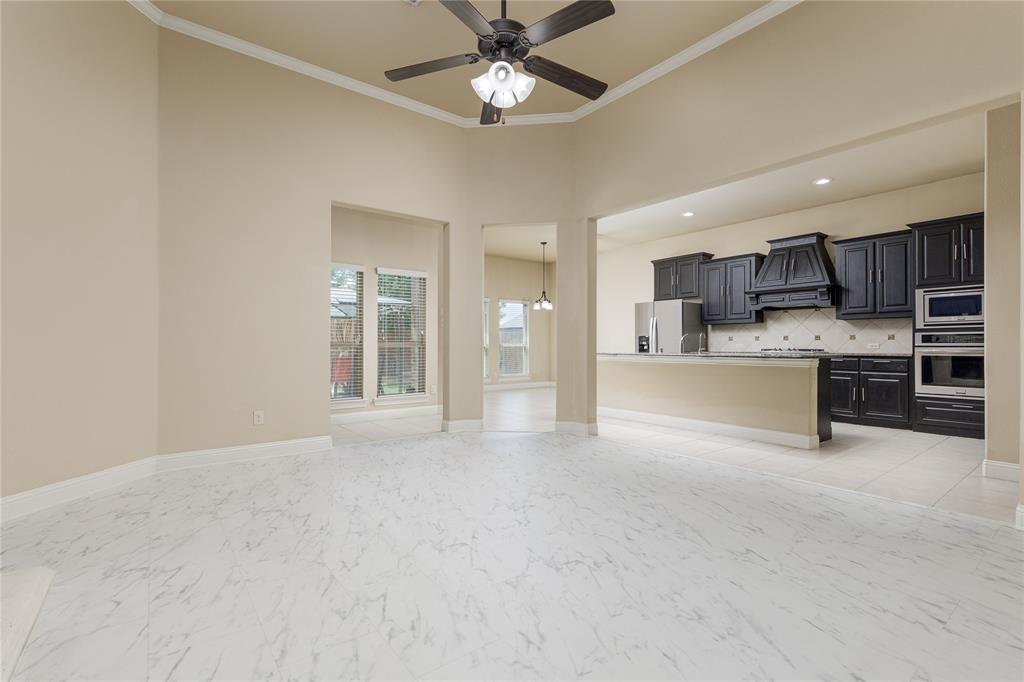 404 Tanner Square McKinney, TX 75072 - Photo 9 of 34 Unfurnished living room featuring crown molding, ceiling fan, light marble finish flooring, baseboards, and a towering ceiling