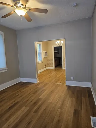 a view of an empty room with wooden floor and a window