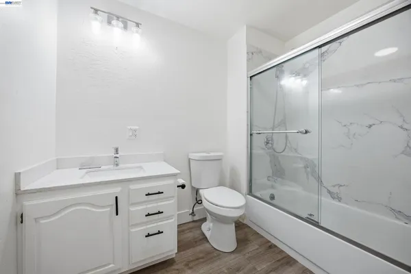 a bathroom with a granite countertop sink a toilet and shower