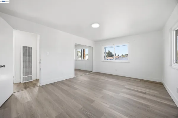 an empty room with wooden floor and windows