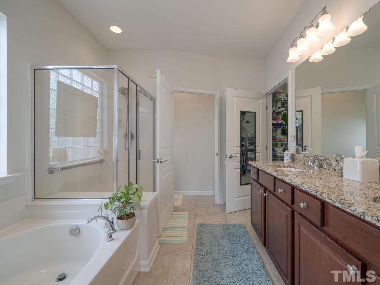 724 Eldridge Loop Cary, NC 27519 - Photo 22 of 38 a bathroom with a granite countertop sink a mirror and a bathtub