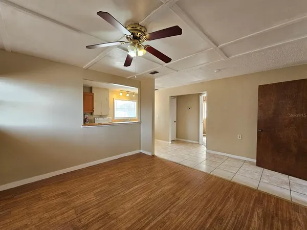 a view of an empty room with wooden floor and a ceiling fan