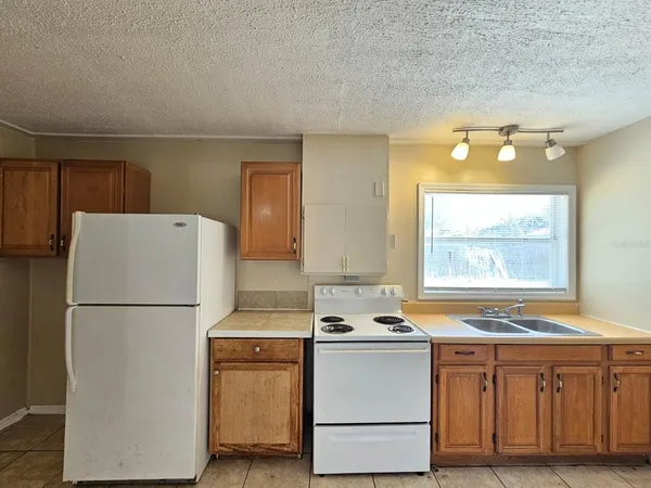 a kitchen with granite countertop white refrigerator sink and cabinets