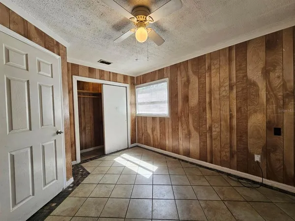 a view of an empty room with window and chandelier fan