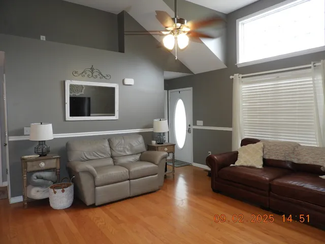 an empty room with wooden floor windows and flat screen tv