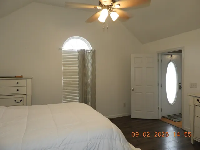 a view of an empty room with a chandelier fan and a window
