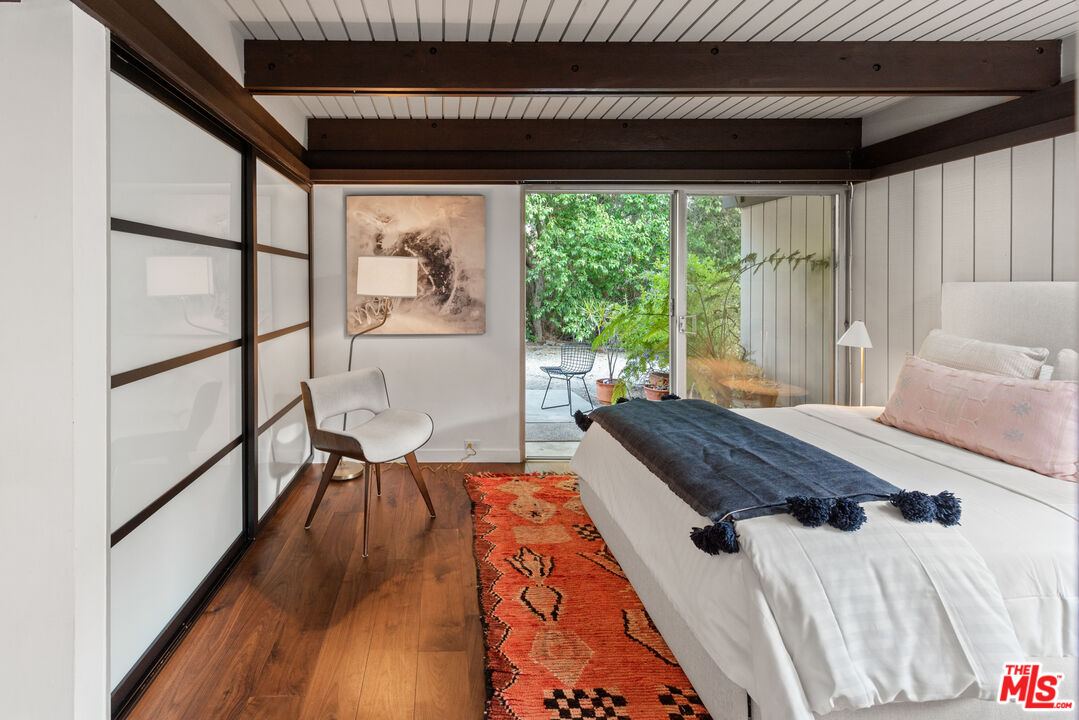 1030 Rivas Canyon Road Pacific Palisades, CA 90272 - Photo 22 of 42 a bedroom with a bed and a large window with wooden floor