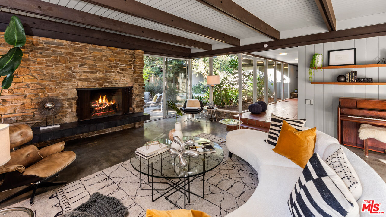 1030 Rivas Canyon Road Pacific Palisades, CA 90272 - Photo 5 of 42 a living room with furniture a fireplace and a floor to ceiling window