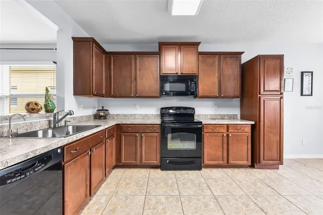 a kitchen with stainless steel appliances granite countertop a sink stove refrigerator and cabinets