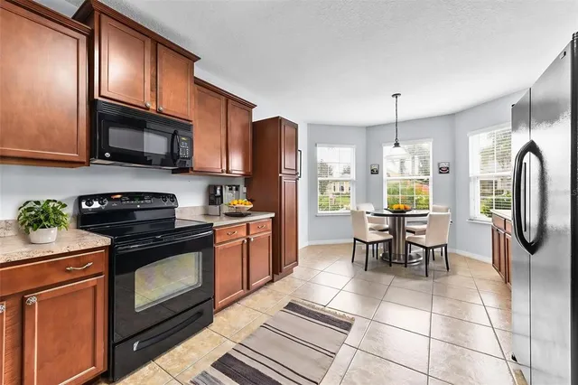 a kitchen with stainless steel appliances granite countertop a stove top oven a sink dishwasher a dining table and chairs with wooden floor