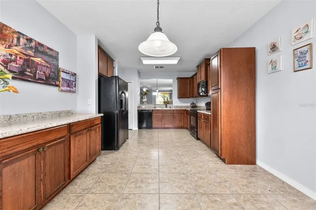a large kitchen with stainless steel appliances kitchen island granite countertop a refrigerator and a sink