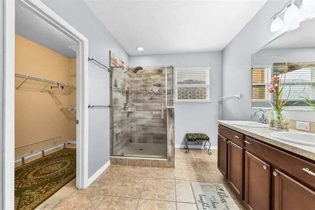 a bathroom with a granite countertop sink a mirror and shower