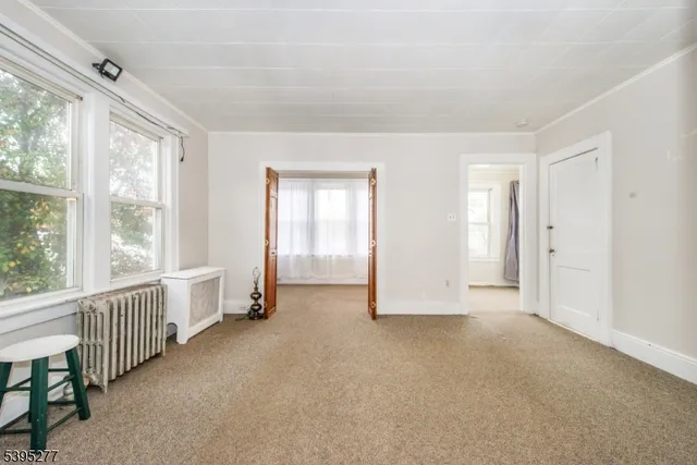 an empty room with chandelier fan and windows