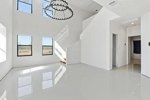 a view of an empty room with chandelier fan and window