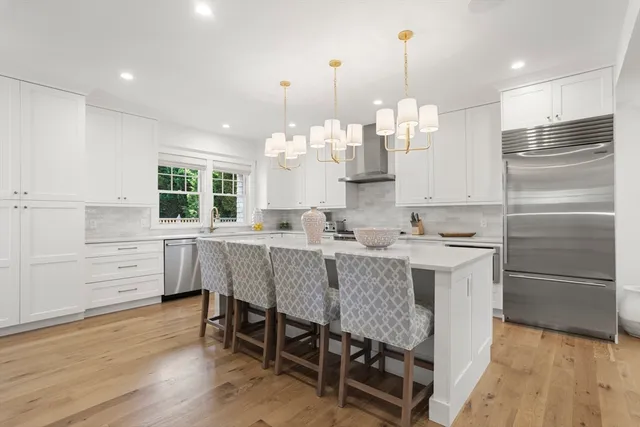 a kitchen with stainless steel appliances granite countertop a table chairs and a refrigerator